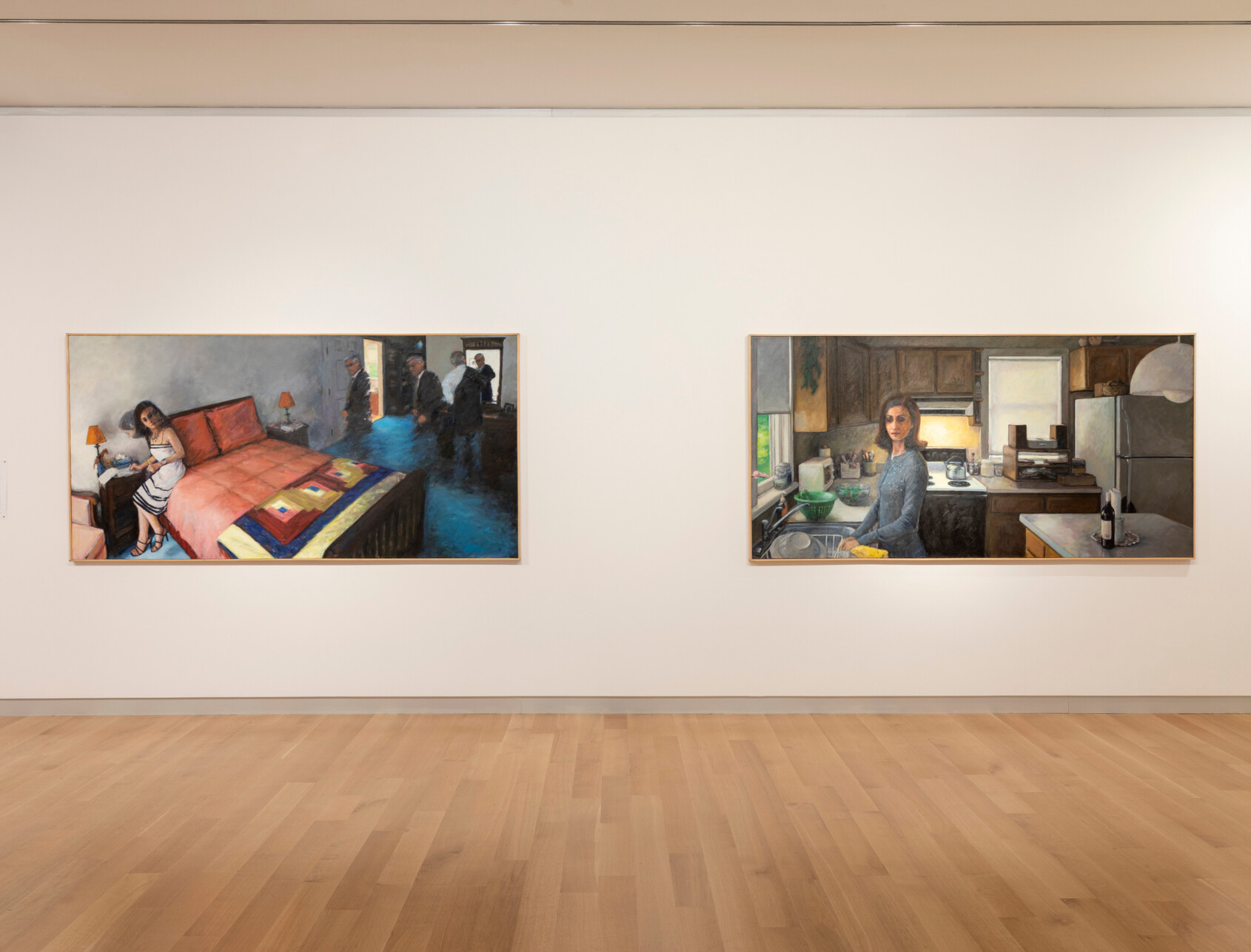 Two large paintings hang on a white gallery wall above a light wood floor. The left painting shows a woman on a bed, while the right painting depicts a woman standing at a kitchen sink.